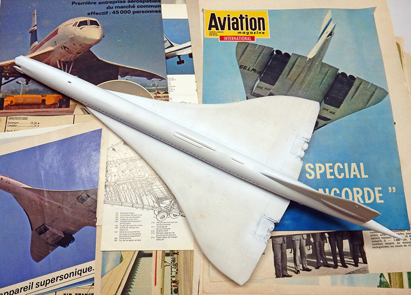 Maquette du Concorde en cours de montage posée sur des revues d'aviation et plans