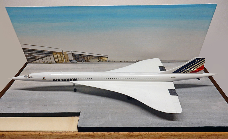 Maquette du Concorde Air France blanc sur diorama avec décor d'aéroport peint en arrière-plan