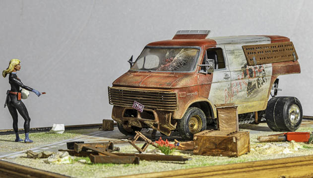 Diorama d'un van rouillé abandonné et figurine féminine en combinaison, sur socle de débris