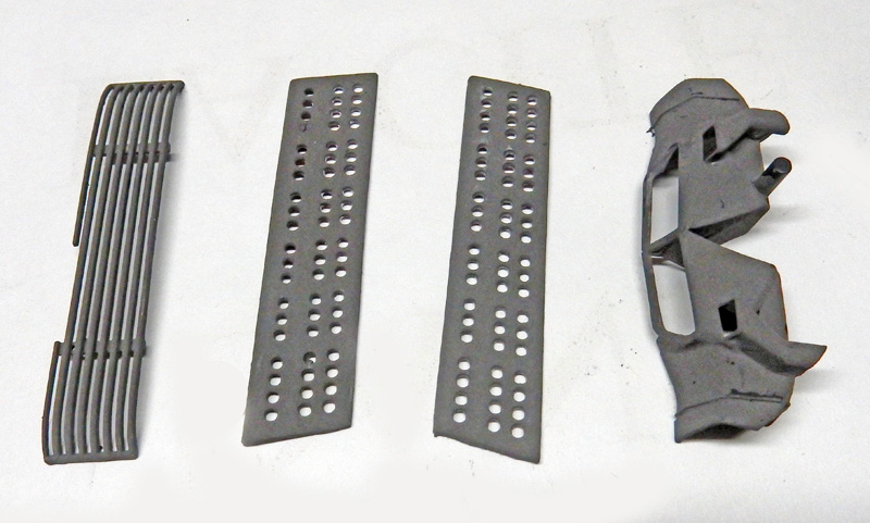 Pièces de maquette grises avec grilles et plaques perforées posées sur fond clair