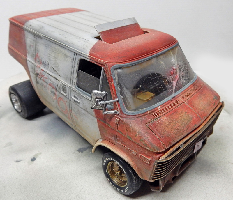 Maquette de van américain rouge et blanc vieilli, vitres fissurées et carrosserie patinée par la rouille