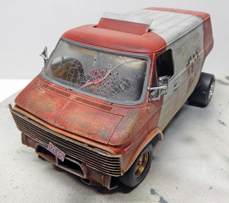 Maquette de van rouge vieilli et rouillé au pare-brise criblé d'impacts, vue avant