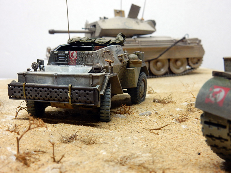 Maquette de voiture blindée britannique et chars sur diorama désertique évoquant la bataille de Gazala