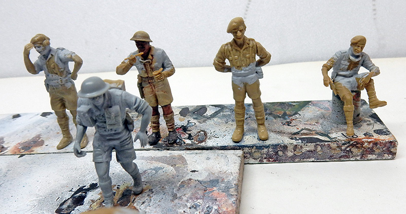 Figurines de soldats britanniques en cours de peinture, certaines en apprêt gris, d'autres beige