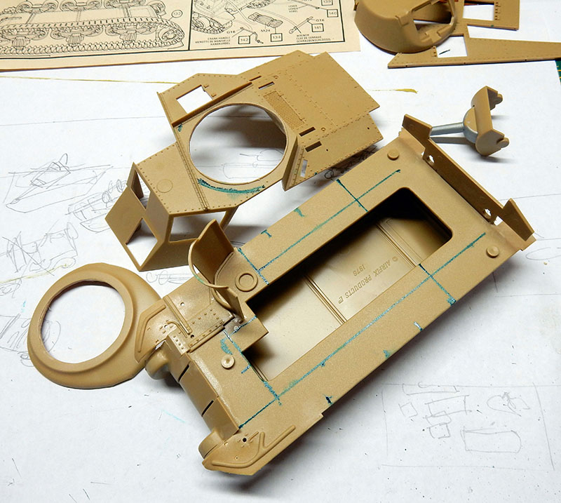 Pièces de maquette de char peintes en sable posées sur la notice de montage