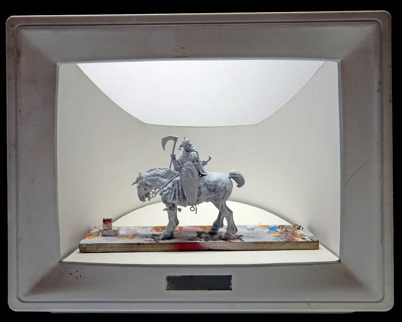 Figurine de cavalier guerrier à la faux en apprêt gris dans une boîte à diorama improvisée