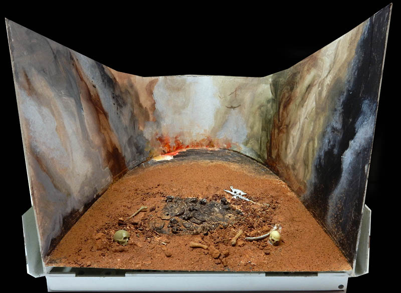 Boîte à diorama ouverte au décor peint avec sol de terre ocre, ossements et crânes