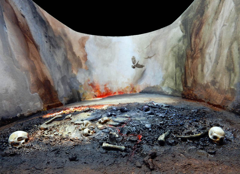 Boîte à diorama avec fond peint, sol jonché de crânes et d'ossements devant des flammes