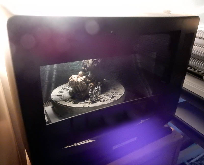 Diorama éclairé présenté dans une boîte vitrée sombre avec reflets violets