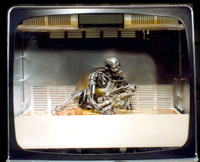 Diorama dans une boîte présentant un endosquelette de Terminator métallique armé sur fond futuriste