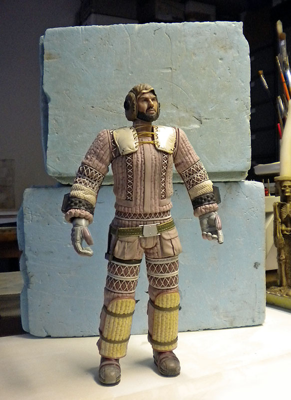 Figurine de guerrier barbu en armure matelassée devant des blocs de mousse bleue