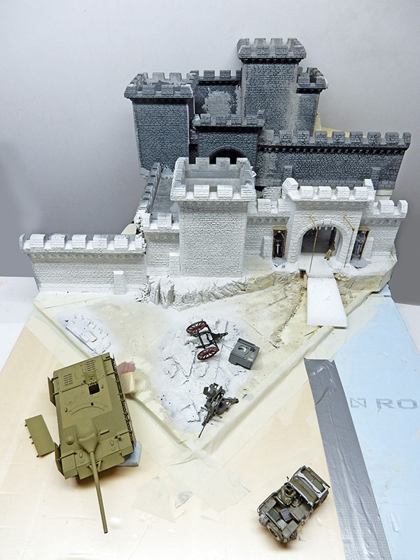 Maquette de château en cours de montage, blindés non peints posés devant les murailles