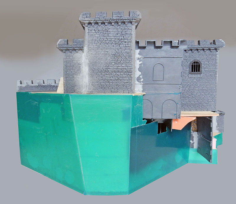 Structure de château en carton-plume peinte en gris, montée sur socle vert en construction