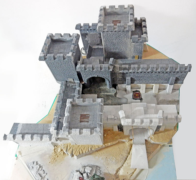 Château médiéval en polystyrène sculpté, tours et remparts en cours de peinture, socle nu