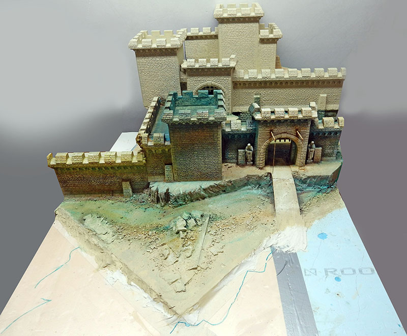 Château médiéval en cours de peinture sur socle, terrain sculpté et sentier d'accès