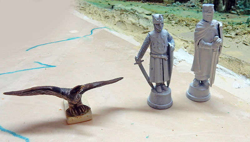 Aigle en bronze et deux figurines de chevaliers non peintes posés sur l'établi