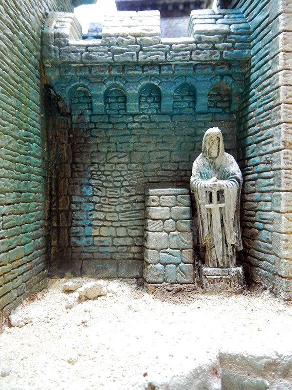 Statue de moine sculptée adossée aux murs de pierre patinés d'une cour intérieure