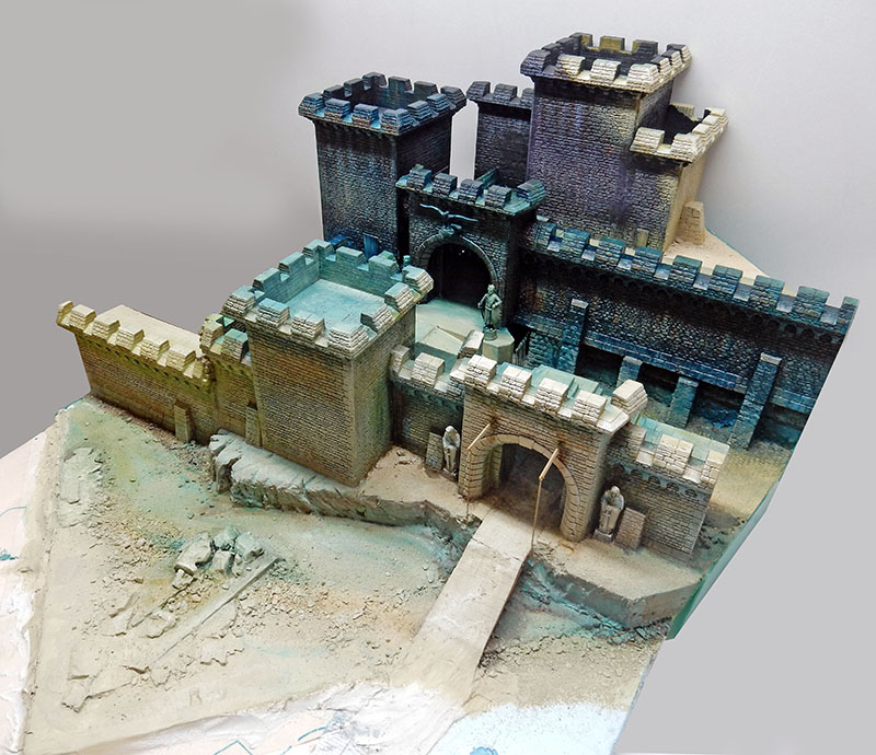 Château fortifié en cours de peinture, murs bleutés, pont-levis et socle encore brut