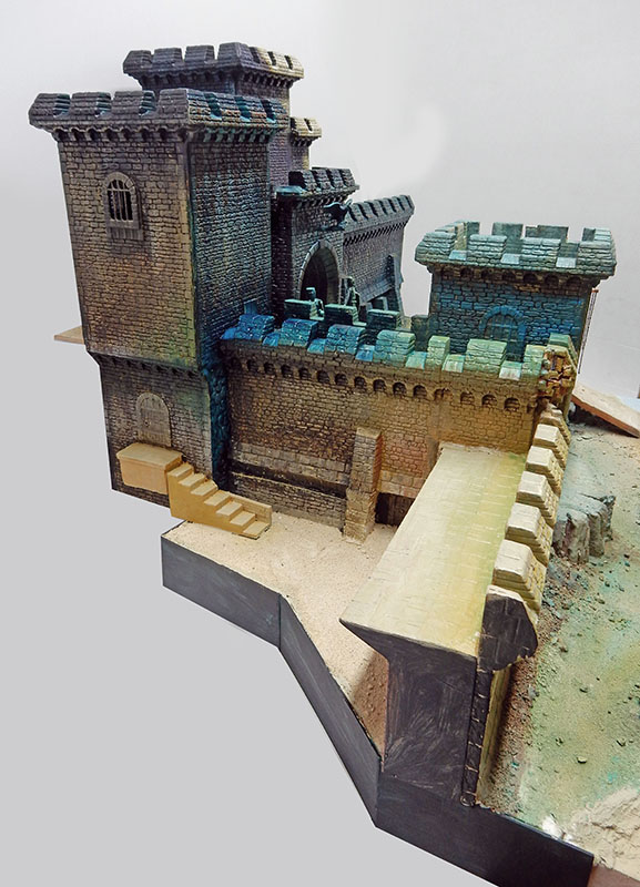 Château fortifié en cours de peinture, tours crénelées et rempart sur socle inachevé