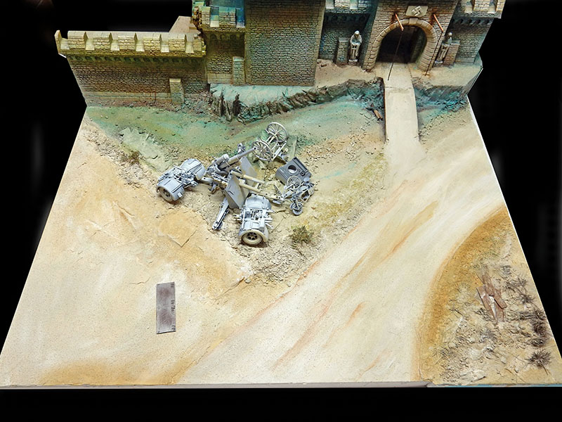 Diorama en cours : canon en pièces détachées devant les remparts, terrain sablonneux peint