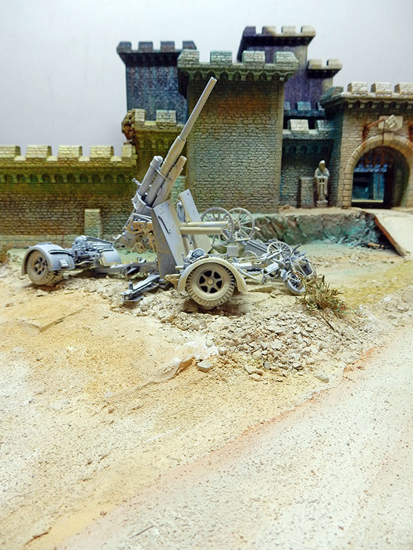 Diorama en cours : canon antiaérien gris sur terrain sableux devant les remparts du château