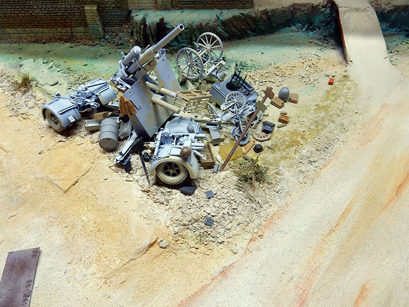 Canon de 88 mm et matériel abandonnés sur un talus sableux, décor du diorama en construction