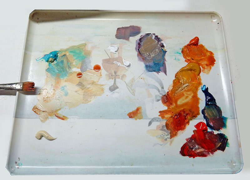 Palette en verre chargée de peintures à l'huile mélangées, avec pinceau plat usagé