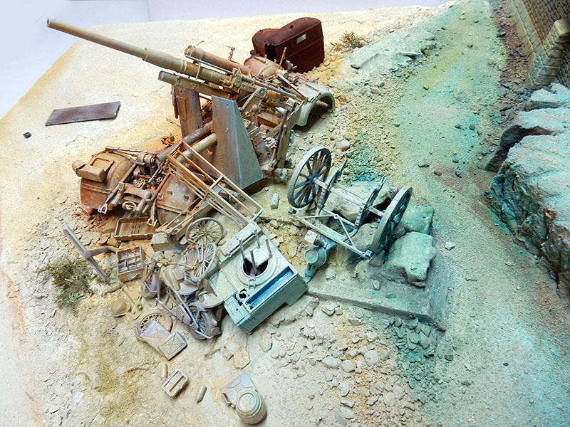 Diorama en cours de montage : canon 88 mm et pièces éparses sur terrain sablonneux