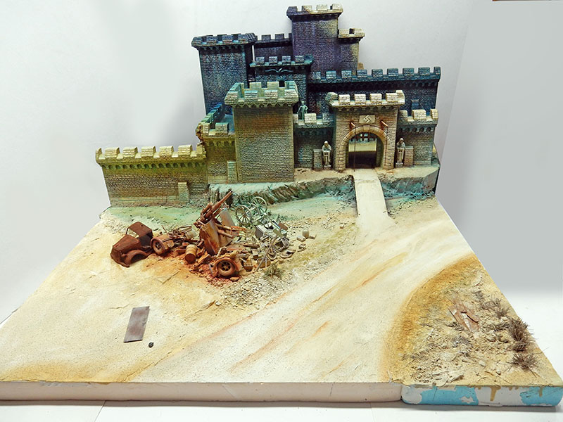 Diorama en cours : château fortifié, route sablonneuse et épaves de véhicules militaires