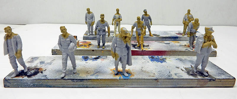 Figurines de soldats sous-couchées en gris, collées sur des socles de peinture provisoires