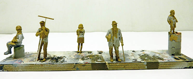 Cinq figurines en cours de sculpture posées sur un support de travail improvisé