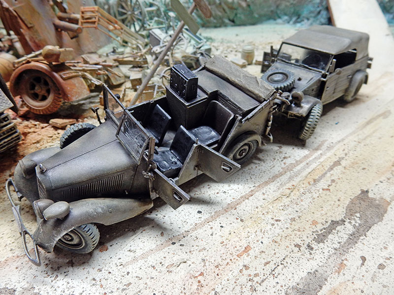 Deux véhicules allemands portes ouvertes dans un diorama de ruines, gravats et ferraille