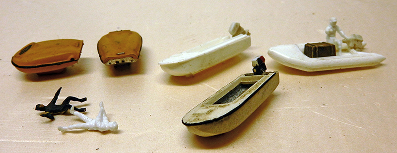 Petites maquettes de canots et figurines de plongeurs miniatures posés sur un plan de travail