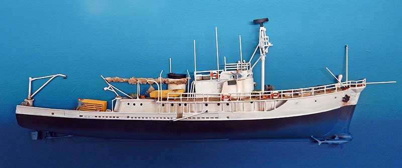 Maquette du navire océanographique Calypso de Cousteau vue de profil sur fond bleu