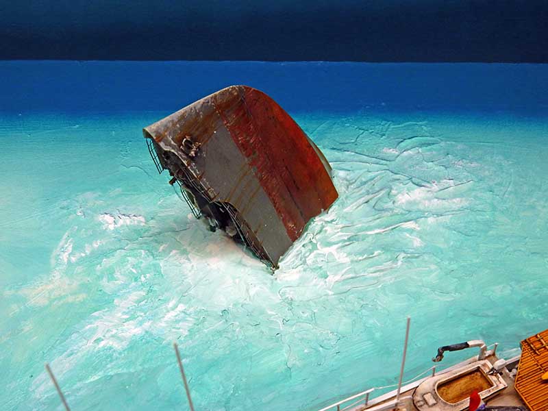 Diorama de maquettisme montrant une épave de navire émergeant d'une mer turquoise