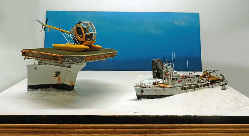 Diorama de la Calypso et hélicoptère jaune sur plateforme, navire océanographique sur mer