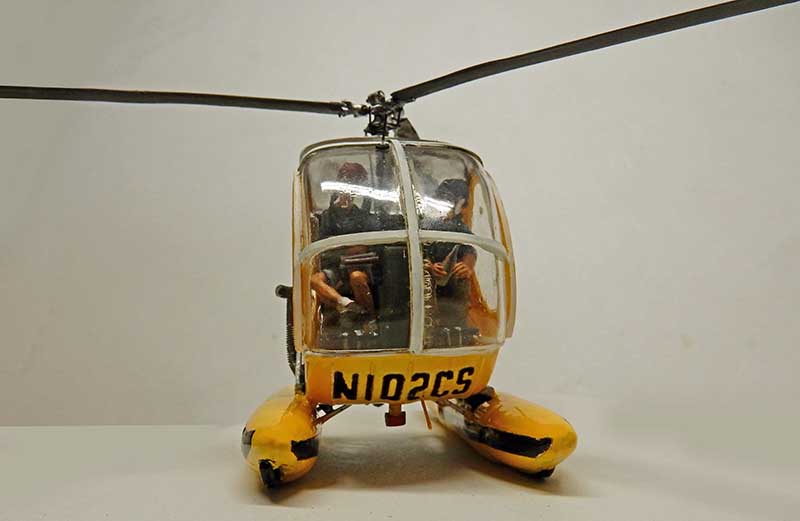 Maquette d'hélicoptère jaune à flotteurs immatriculé N102CS avec deux figurines dans le cockpit