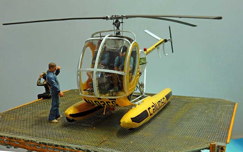 Maquette d'hélicoptère jaune Calypso sur flotteurs avec figurines sur la plateforme du diorama Cousteau