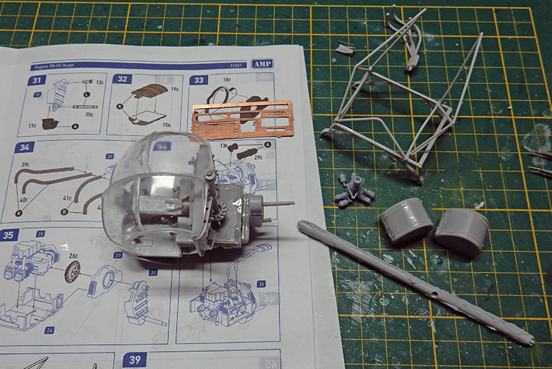 Maquette d'hélicoptère Hughes en cours d'assemblage avec notice, pièces grises et photodécoupe sur tapis de découpe