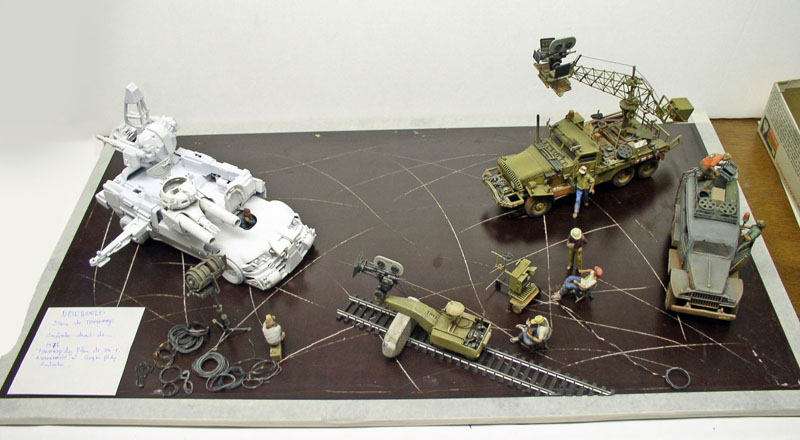 Diorama de scène de tournage avec véhicules militaires maquettés, rails de caméra et figurines de techniciens