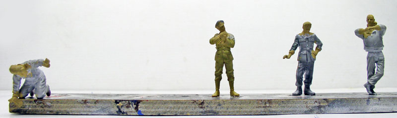 Figurines de personnages en cours de peinture alignées sur un support pour diorama de tournage
