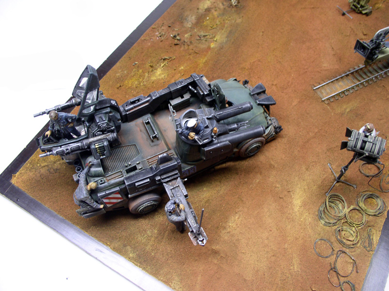 Diorama maquette de véhicule blindé sci-fi avec figurines, projecteur et rails sur sol désertique