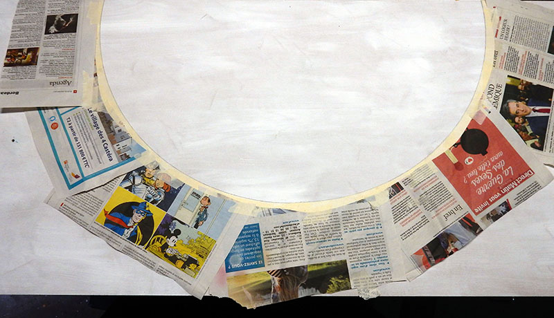 Pièce de maquette en arc de cercle protégée par du papier journal sur l'établi