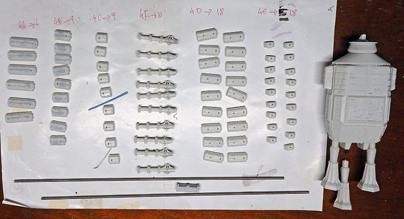 Pièces de maquette triées et numérotées sur une feuille à côté d'un module assemblé
