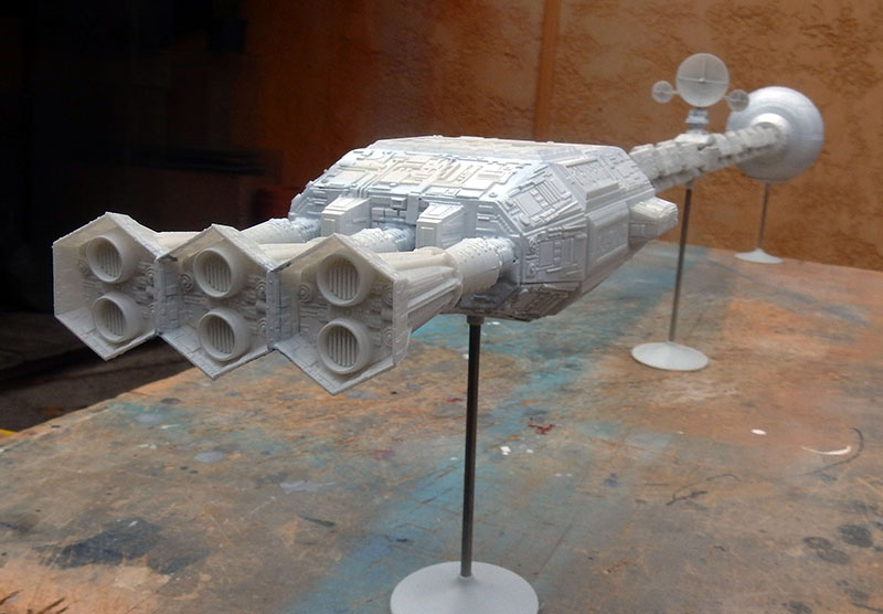 Maquette du vaisseau spatial Discovery en cours de montage, posée sur supports sur un établi