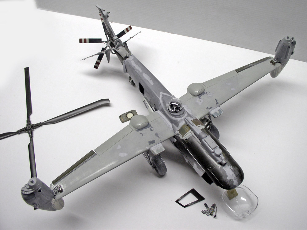 Maquette d'hélicoptère gris en cours de montage avec rotor principal et verrière détachés