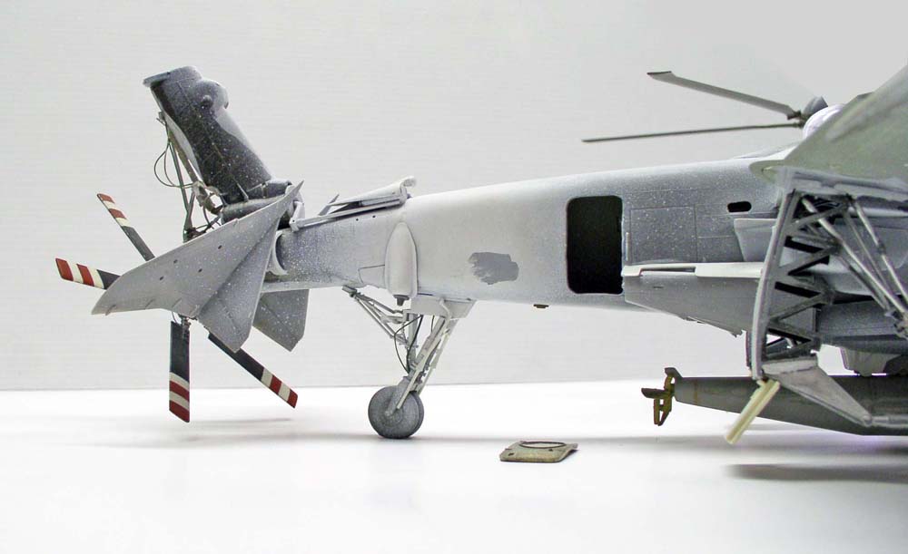 Maquette d'hélicoptère militaire gris en construction montrant le rotor de queue et le fuselage arrière