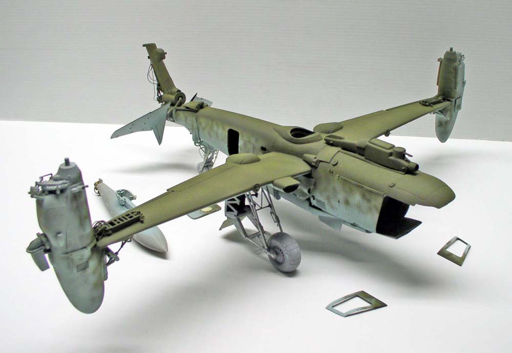 Maquette d'aéronef convertible vert kaki avec rotors basculants et trains d'atterrissage, pièces détachées posées à côté