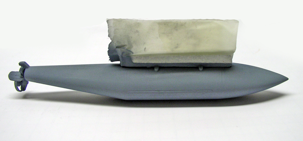 Coque grise de maquette de navire avec bloc de mousse maintenu par adhésif en cours de montage