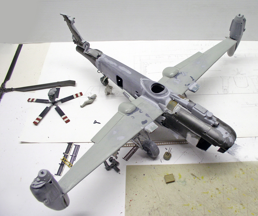 Maquette d'hélicoptère de combat gris en cours de montage avec rotor et pièces détachées